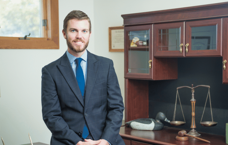 Eric Preston, lawyer, in a suit and tie standing in front of a desk